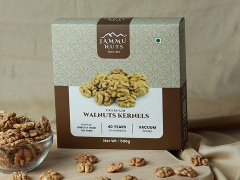 Box of Jammu Nuts walnuts kernels with a glass container and scattered nuts on a wooden surface.